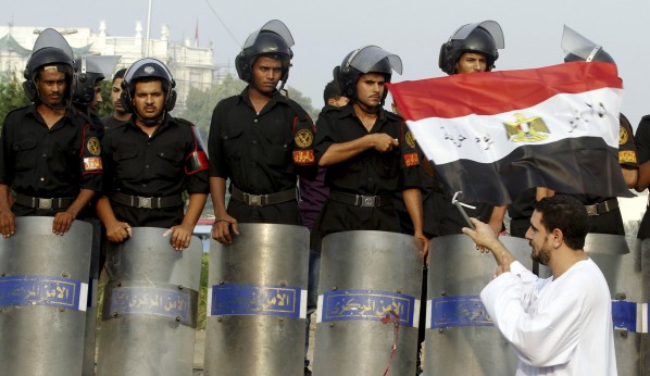 A man waves an Egyptian flag in front of riot police during Eid al-Fitr celebrations on Tahrir square in Cairo